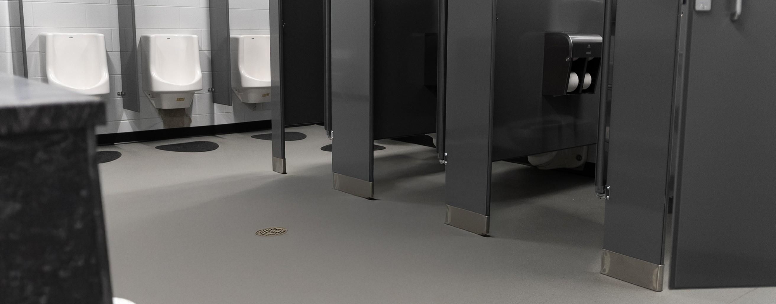 A shot of a restroom with stalls and urinals and HydroGrip installed.